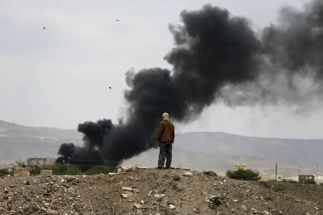 A man looks at smoke billowing from the military academy during a Saudi-led air strike in Yemen's capital Sanaa September 2, 2015. (Photo by Khaled Abdullah/Reuters)