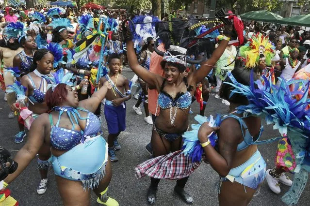 Dancers perform for spectators during the West Indian Day Parade, Monday, September 1, 2014 in the Brooklyn borough of New York. (Photo by Mark Lennihan/AP Photo)