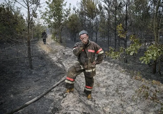 A firefighter reacts as he works to extinguish a forest fire near Kiev, Ukraine, September 3, 2015. About 15 hectares of forest have been burnt in a fire that started yesterday evening near the Ukrainian capital, emergencies service said. (Photo by Gleb Garanich/Reuters)