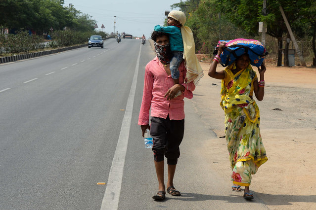 A family of migrant workers from the Indian state of Maharashtra walk along a National Highway 44 to reach their hometowns during a government-imposed nationwide lockdown as a preventive measure against the COVID-19 coronavirus on the outskirts of Hyderabad on April 28, 2020. (Photo by Noah Seelam/AFP Photo)