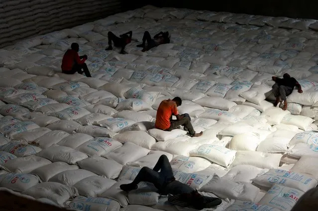Labourers rest as they offload bags of grains as part of relief food that was sent from Ukraine at the World Food Program (WFP) warehouse in Adama town, Ethiopia om September 8, 2022. (Photo by Tiksa Negeri/Reuters)