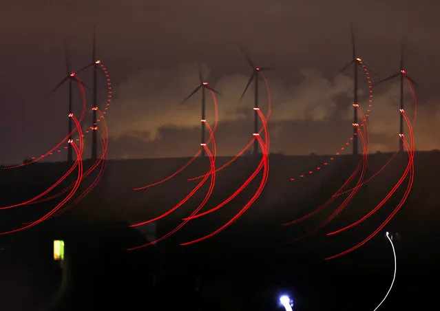 In this photo taken with slow shutter speed and with the lens being moved during the exposure red warning lights for aircrafts that are fixed at wind power plants shine in the night in Kirchheimbolanden, Germany, early Monday, October 9, 2017. (Photo by Michael Probst/AP Photo)