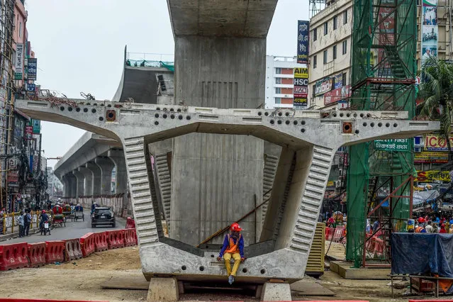 A labourer of the Dhaka Metro Rail project sits on a building material on a street during a government-imposed nationwide lockdown as a preventive measure against the COVID-19 coronavirus, in Dhaka on April 22, 2020. (Photo by Munir Uz Zaman/AFP Photo)