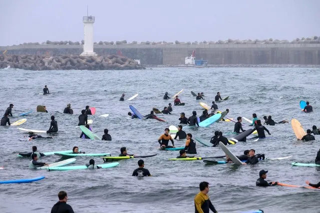  In a photo taken on May 9, 2020 surfers gather in the water at Jukdo beach, near Sokcho. (Photo by Ed Jones/AFP Photo)