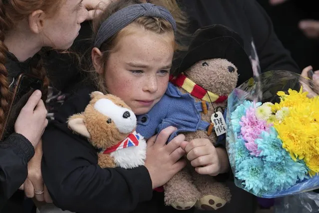 A young girl holds a Paddington bear and a Corgi dog stuffed toys while waiting to watch the Procession of Queen Elizabeth's coffin from the Palace of Holyroodhouse to St Giles Cathedral on the Royal Mile in Edinburgh, Scotland, Monday, September 12, 2022. At the Cathedral there will be a Service to celebrate the life of the Queen and her connection to Scotland. (Photo by Jon Super/AP Photo/Pool)