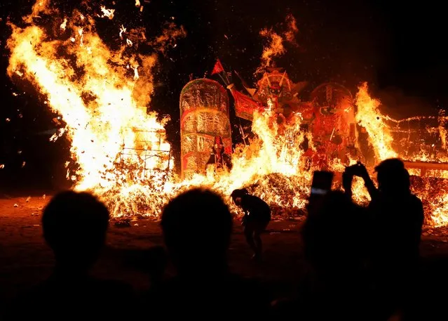 People watch a giant paper statue of the Chinese deity “Da Shi Ye” or “Guardian God of Ghosts” burn during the Chinese Hungry Ghost Festival, in Cheras, Selangor, Malaysia August 13, 2022. (Photo by Hasnoor Hussain/Reuters)