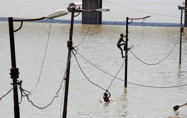 A boy climbs a partially submerged electric pole as he plays with others on the flooded banks of Ganga river, in Allahabad, India, August 21, 2016. (Photo by Jitendra Prakash/Reuters)