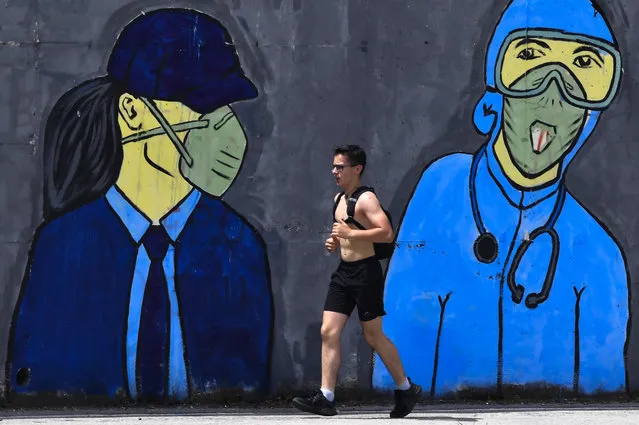 A man runs in front of a mural inspired by the COVID-19 coronavirus pandemic in Skopje, Republic of North Macedonia, 08 June 2020. After an 80-hour curfew, many people left their homes. According to reports, the number of newly infected COVID-19 patients in the North Macedonia is still more than one hundred per day in the last two weeks. The government is considering to continue with preventive measures in the country. (Photo by Georgi Licovski/EPA/EFE)