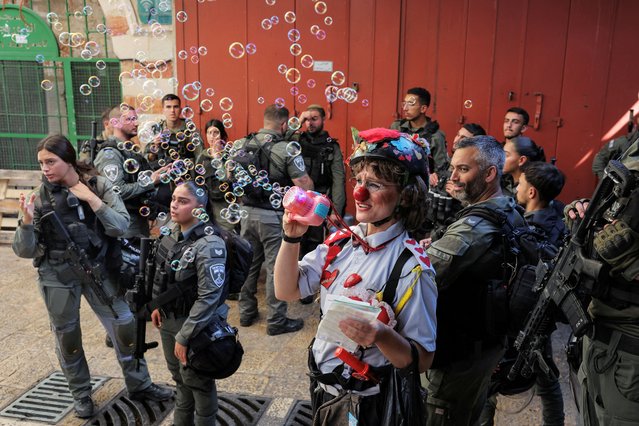 A clown blows bubbles as Israeli border police gather during the annual Jerusalem Day march, in Jerusalem's Old City on June 5, 2024. (Photo by Marko Djurica/Reuters)