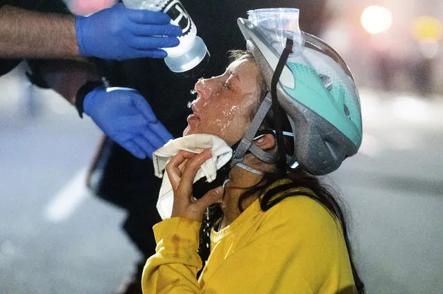 A medic treats Black Lives Matter protester Lacey Wambalaba after exposure to chemical irritants deployed by federal officers at the Mark O. Hatfield United States Courthouse on Friday, July 24, 2020, in Portland, Ore. (Photo by Noah Berger/AP Photo)
