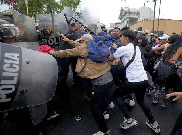 Supporters of ousted President Pedro Castillo clash with police during a protest in Lima, Peru, Thursday, December 8, 2022. Peru's Congress voted to remove Castillo from office Wednesday and replace him with the vice president, shortly after Castillo tried to dissolve the legislature ahead of a scheduled vote to remove him. (Photo by Fernando Vergara/AP Photo)