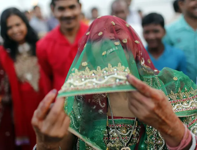 A woman laughs as she covers her face after worshipping the Sun god Surya on the banks of the river Yamuna during the Hindu religious festival of Chatt Puja in New Delhi October 29, 2014. (Photo by Anindito Mukherjee/Reuters)