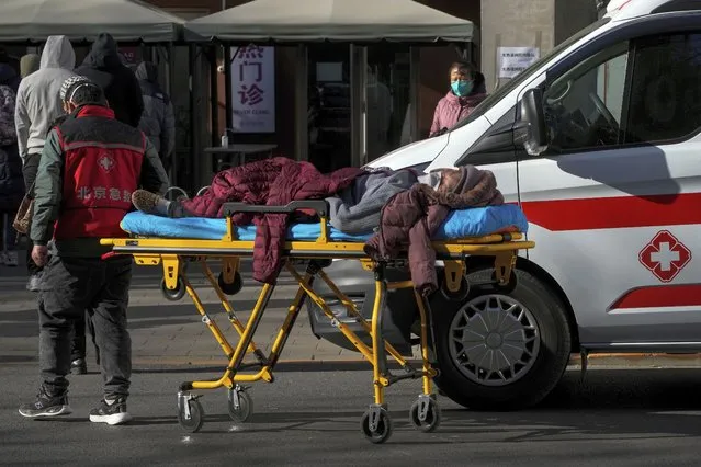 An elderly woman on a stretcher is wheeled into the fever clinic at a hospital in Beijing, Sunday, December 11, 2022. Facing a surge in COVID-19 cases, China is setting up more intensive care facilities and trying to strengthen hospitals as Beijing rolls back anti-virus controls that confined millions of people to their homes, crushed economic growth and set off protests. (Photo by Andy Wong/AP Photo)