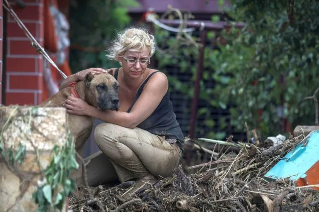 A woman hugs her dog at the village of Bourtzi, following flash floods on the island of Evia, Greece on August 10, 2020. (Photo by Sotiris Dimitropoulos/Eurokinissi via Reuters)