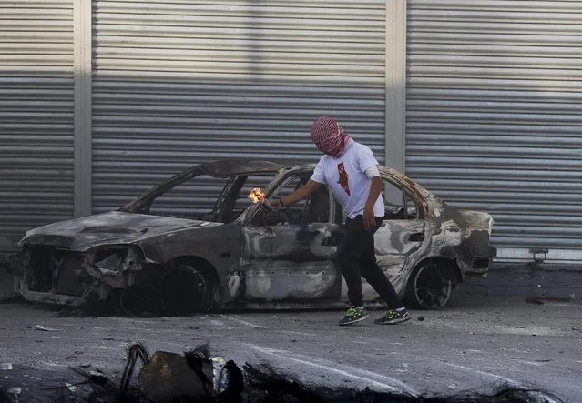 A Palestinian protestor gets ready to throw a molotov cocktail  towards Israeli border police during clashes at a checkpoint between Shuafat refugee camp and Jerusalem October 9, 2015. (Photo by Ammar Awad/Reuters)