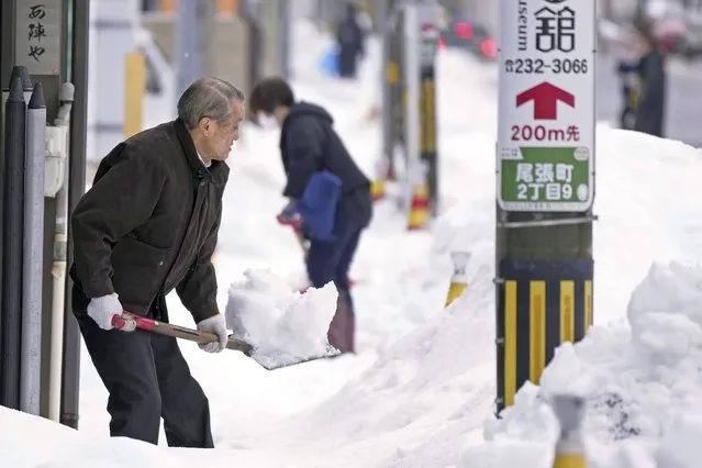 People shovel snow from sidewalks in Kanazawa, in central Japan's Ishikawa prefecture, on December 24, 2022. (Kyodo News via AP Photo)