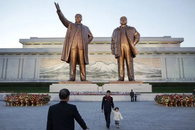 A man and his grandchildren prepare to pay their respects at statues of North Korea founder Kim Il Sung (L) and late leader Kim Jong Il in Pyongyang October 11, 2015. (Photo by Damir Sagolj/Reuters)