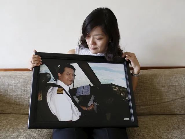 Ivy Loi, wife of MH17 co-pilot Eugene Choo, poses for a photograph with a picture of her husband, at home in Seremban, near Kuala Lumpur, Malaysia, October 13, 2015. Malaysia Airlines Flight 17 was shot down over eastern Ukraine by a Russian-made Buk missile, the Dutch Safety Board concluded on Tuesday in its final report on the July 2014 crash that killed all 298 people on board. (Photo by Olivia Harris/Reuters)