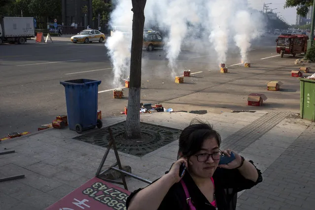 A woman plugs her ears as firecrackers go off in the streets of Yanjiao, a rapidly expanding satellite city of over 700,000 people, outside Beijing, on May 21, 2016. (Photo by Michael Robinson Chavez/The Washington Post)