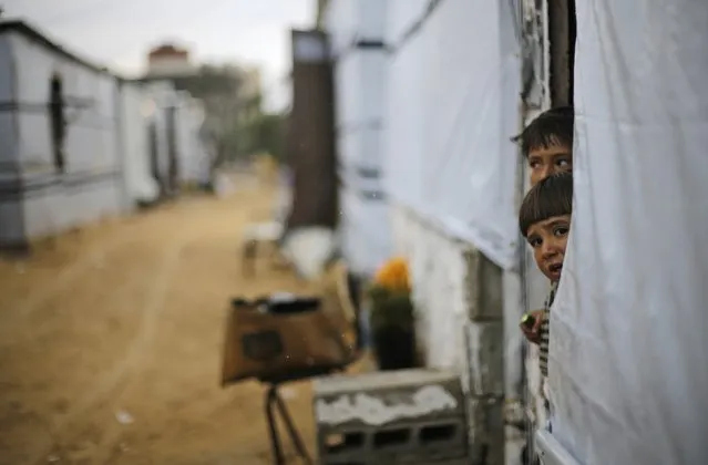Palestinian children, who live in a container as a temporary replacement for their house that witnesses said was destroyed by Israeli shelling during the most recent conflict between Israel and Hamas, look out on a rainy day in the east of Khan Younis in the southern Gaza Strip November 16, 2014. (Photo by Ibraheem Abu Mustafa/Reuters)