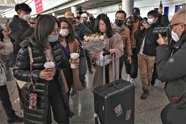 A woman holding a bouquet of flowers reacts with her relatives surrounded by journalists as she arrives from Hong Kong, at Terminal 3 international arrival hall of the Beijing Capital International Airport in Beijing, Sunday, January 8, 2023. Travelers crossing between Hong Kong and mainland China, however, are still required to show a negative COVID-19 test taken within the last 48 hours, a measure China has protested when imposed by other countries. (Photo by Andy Wong/AP Photo)