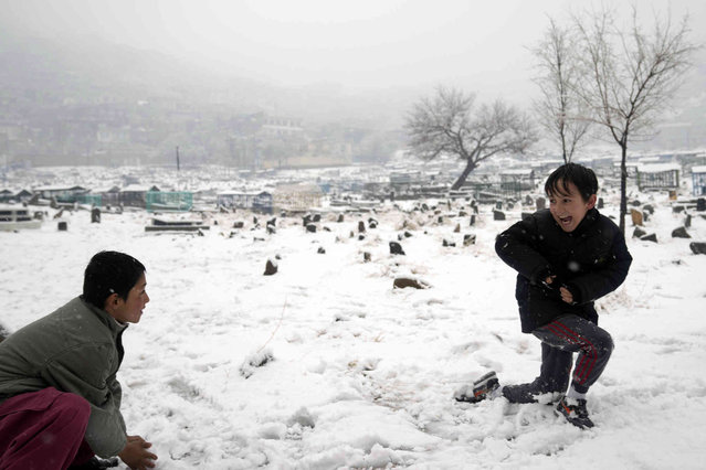 Afghan boys play in a cemetery during snowfall in Kabul, Afghanistan Thursday, December 29, 2022. (Photo by Ebrahim Noroozi/AP Photo)