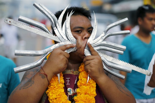 A devotee of the Chinese Samkong Shrine walks with knives and metal objects pierced through his cheeks during a procession celebrating the annual vegetarian festival in Phuket, Thailand, October 16, 2015. (Photo by Jorge Silva/Reuters)