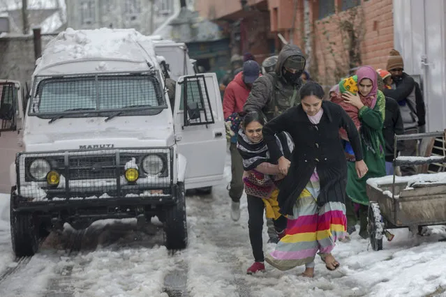 Family members of Indian paramilitary personnel living near the site of a gunbattle run towards waiting vehicles after they are escorted out in Srinagar, Indian controlled Kashmir, Monday, February 12, 2018. Two gunmen have opened fire near a paramilitary camp in the main city of Indian controlled Kashmir killing at least one soldier. The attack comes hours after government troops ended a two day gunbattle with three armed gunmen at an army camp in another part of the disputed region. (Photo by Dar Yasin/AP Photo)