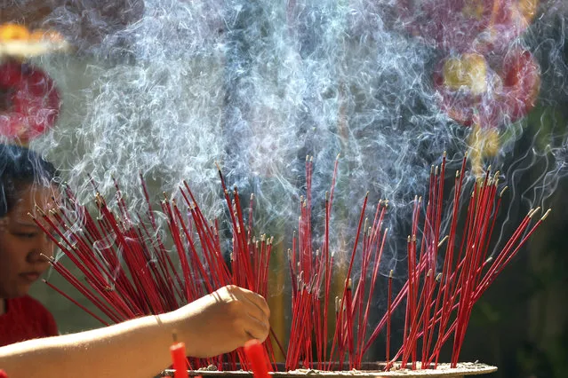 A woman places incense sticks during celebrations of the Lunar New Year at a temple in Bali, Indonesia, Friday, February 16, 2018. (Photo by Firdia Lisnawati/AP Photo)