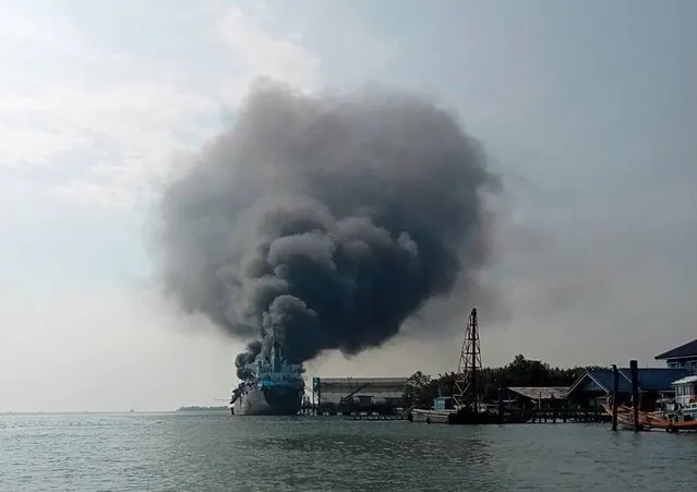 A handout photo made available by the Eastern Fire Volunteer Club shows an oil tanker burning after an explosion at a dockyard on the Mae Klong river in Samut Songkram province, Thailand, 17 January 2023. At least eight people were missing and several people injured, including many in nearby houses that were damaged, after the Smooth Sea 22 oil tanker exploded, the Marine Department reported. (Photo by Eastern Fire Volunteer Club/EPA/EFE)