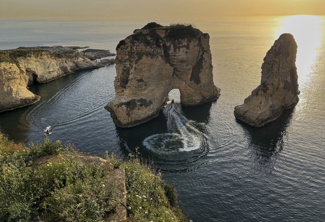 A man rides his jet ski under the landmark Rock of Raouche, also known as Pigeons' Rock, amid warm weather in Beirut, Lebanon, Friday, March 28, 2025. (Photo by Hussein Malla/AP Photo)