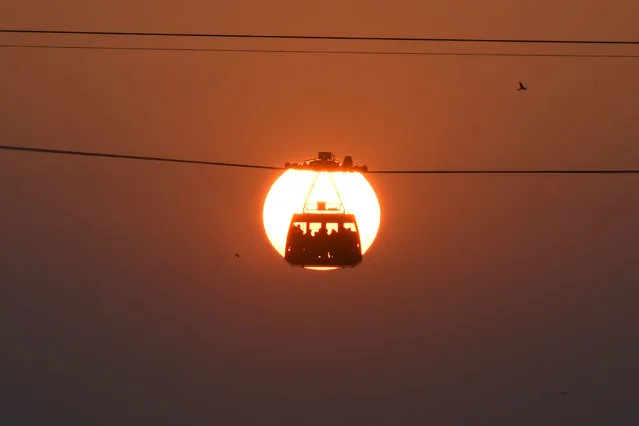 People travel in a cabin on India's longest river cable car connecting the northern and southern banks of the Brahmaputra river at sunset, in Guwahati on October 28, 2020. (Photo by Biju Boro/AFP Photo)