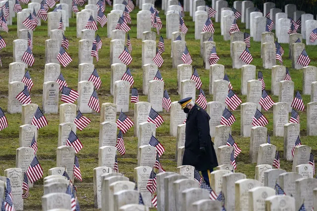 Retired U.S.Army veteran Bill MacCully walks among flag-covered graves in the Veterans Cemetery of Evergreen Washelli Memorial Park on Veterans Day, Wednesday, November 11, 2020, in Seattle. (Photo by Elaine Thompson/AP Photo)