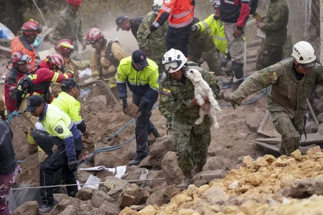 A soldier carries a dog found among the rubble of buildings destroyed by a deadly landslide that buried dozens of homes in Alausi, Ecuador, Monday, March 27, 2023. (Photo by Dolores Ochoa/AP Photo)