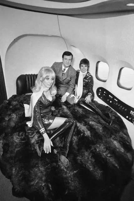 In this February 17, 1970 file photo, Playboy empire magnate Hugh Hefner, center, poses with two of the Playboy Jet Bunnies on large six foot by eight foot elliptical bed after his new $5.5 million aircraft arrived at Burbank Airport in Burbank, Calif. The bed is in Hefner's private quarters in the rear section of the “Big Bunny” plane. (Photo by George Brich/AP Photo)