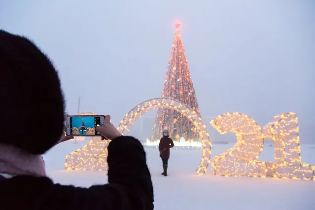 People pose for photographs at a Christmas tree and a 2021 sign in Lenin Square in freezing conditions of minus 43 degrees Celsius in the city of Yakutsk, Sakha (Yakutia) on December 13, 2020. Located in Russia's Far East, Yakutia is known for its severe climate. (Photo by Yevgeny Sofroneyev/TASS)