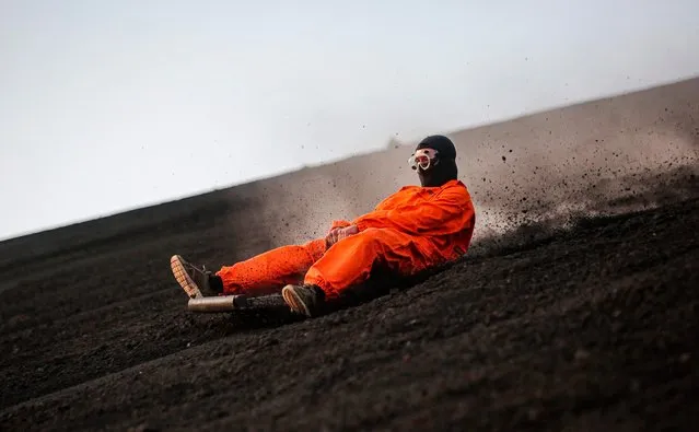 A tourist slides down the slopes of the Cerro Negro volcano, the youngest in Central America (167 years old) and one of the most active in the country, in Leon, Nicaragua on March 22, 2022. Volcano boarding at the Cerro Negro attracts hundreds of visitors who want to undergo extreme experiences, a relief for tourism, which was hit doubly by the pandemic and the political crisis that submerges Nicaragua since 2018. (Photo by Oswaldo Rivas/AFP Photo)