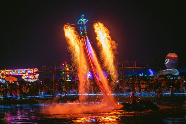 A folk artist on a flyboard shakes iron nets with hot charcoals to create sparks during Huohu (fire pot) performance at Weiran Flower Sea scenic area during the National Day holiday on October 6, 2024 in Chengdu, Sichuan Province of China. (Photo by VCG/VCG via Getty Images)