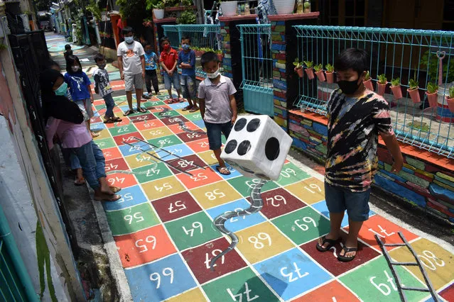 Children gather to play along a path painted with various children’s games at a neighbourhood in Bandung on March 4, 2021. (Photo by Timur Matahari/AFP Photo)