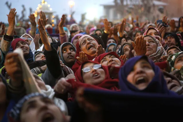 Kashmiri Muslim devotees pray as a priest displays a holy relic of the Prophet Muhammad at the Hazratbal shrine on the occasion of a festival that commemorates the birthday of Prophet Muhammad in Srinagar, Indian-controlled Kashmir, Thursday, December 24, 2015. Thousands of Kashmiri Muslims gathered at the shrine, which houses a relic believed to be a hair from the beard of the prophet. (Photo by Mukhtar Khan/AP Photo)
