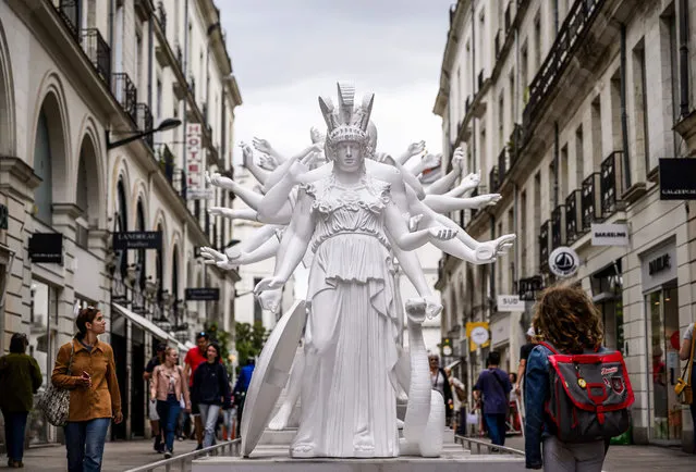 Members of the public walk past the “European Thousand-Arms Classical Sculpture” by Chinese artist Xu Zhen, on July 5, 2023, as part of the “Le Voyage à Nantes” Art Fair. “Le Voyage à Nantes” Art Fair, welcoming around 50 cultural elements on a 12 kilometer-long trail reactivated by artists, architects, designers and garderners, runs from July 1 to September 3. (Photo by Loic Venance/AFP Photo)