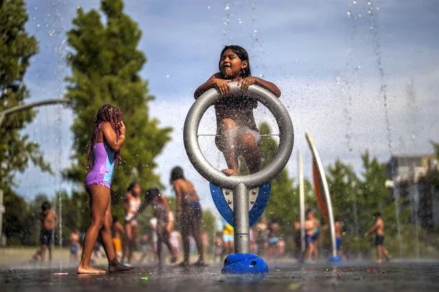 Children cool off at an urban beach of Madrid Rio park in Madrid, Spain, Wednesday, July 12, 2023. More than 10 of Spain's regions are on red alert for the second day of the latest heat wave, with temperatures topping 40 degrees Celsius. (Photo by Manu Fernandez/AP Photo)