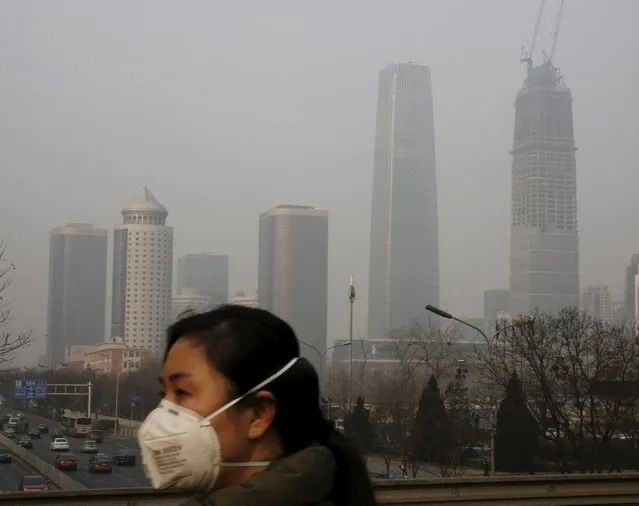 A woman wearing a protective mask makes her way in a business district on a heavily polluted day in Beijing, China January 3, 2016. (Photo by Kim Kyung-Hoon/Reuters)