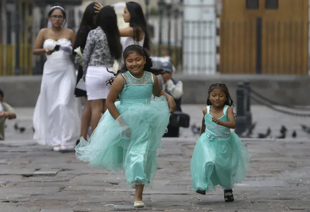 In this Thursday, December 8, 2016 photo, girls race outside the San Francisco church before the start of a first communion ceremony in Lima, Peru, on the Catholic feast day of the Immaculate Conception honoring the Virgin Mary. (Photo by Martin Mejia/AP Photo)
