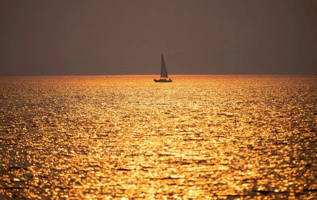 A sailboat makes its way back to harbour as the sun sets behind smoke from wildfires, Thursday, June 29, 2023 in Ottawa, Ontario. (Photo by Adrian Wyld/The Canadian Press via AP Photo)