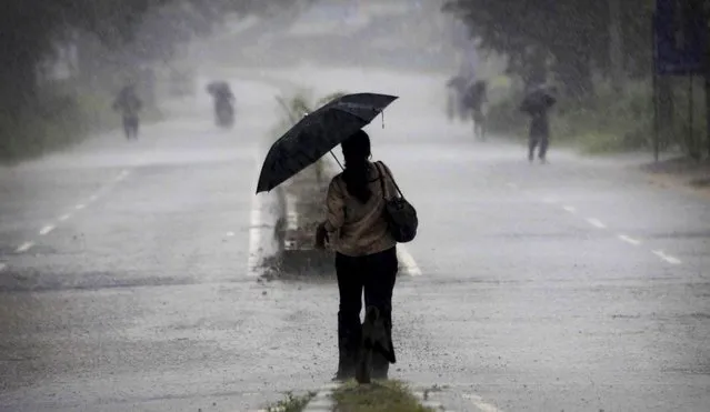 An Indian woman holds an umbrella as she heads towards a cyclone shelter near Chatrapur in Ganjam district about 200 kilometers  (125 miles) from the eastern Indian city Bhubaneswar, India, Saturday, October 12, 2013. Hundreds of thousands of people living along India's eastern coastline were taking shelter Saturday from a massive, powerful cyclone Phailin that was set to reach land packing destructive winds and heavy rains. (Photo by Biswaranjan Rout/AP Photo)