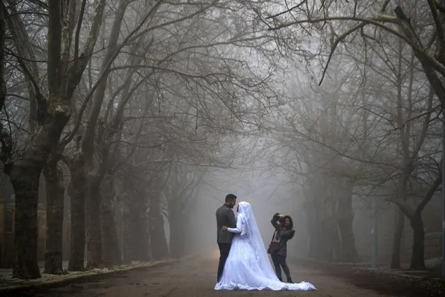 A bride and her groom pose for a photograph during a wedding photoshoot as heavy fog envelope the Sawfar village, Mount Lebanon Governorate of Lebanon, Saturday, April 3, 2021. Lebanese authorities imposed a three-day nationwide curfew as of Saturday morning to try limit the spread of COVID-19 during the Easter holidays. (Photo by Hassan Ammar/AP Photo)
