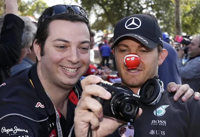 Mercedes Formula One driver Nico Rosberg of Germany wears a red nose for 'Red Nose Day' as he takes a photograph with a fan upon arrival for the first practice session of the Australian F1 Grand Prix at the Albert Park circuit in Melbourne March 13, 2015.  REUTERS/Mark Dadswell