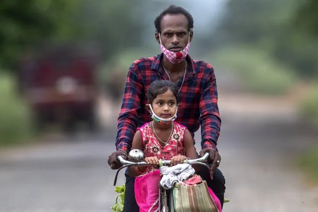 An Indian villager and a child wearing masks on their chin ride on a bicycle on the outskirts of Gauhati, India, Monday, June 7, 2021. (Photo by Anupam Nath/AP Photo)