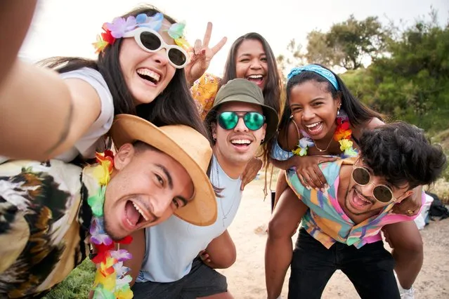 Cheerful and funny selfie of a multiracial group of friends hanging out at a beach festival. Recently graduated colleagues. (Photo by Carlos Barquero/Getty Images)
